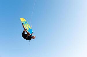 freestyle kiteboarding, freedom you can get. athlete hangs in the air during a trick on a kiteboard, on a clear blue sky photo
