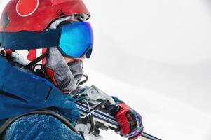 Portrait of confident skier in blue jacket and red helmet standing on top of mountain and holding skis. Happy man enjoying skiing holiday on winter day photo