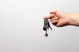 Female Hand holding key with a keychain in the shape of the house. House key on the white background photo