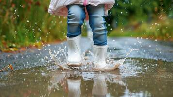 A child jumping in the rain with rubber boots photo