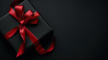 Black gift box with red ribbon on black background photo
