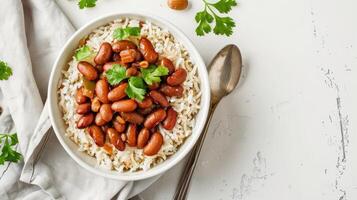A bowl of beans and rice with parsley on a white background photo