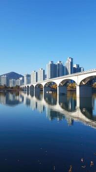 A bridge spanning over a river with tall buildings in the background photo