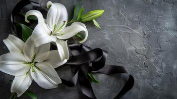 White lilies and black ribbon on a gray background photo