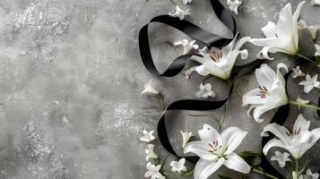 White lilies and black ribbon on a gray background photo
