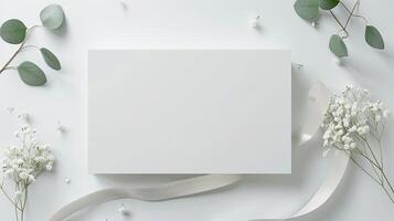 White square card with lily of the valley flowers and ribbon on white background photo