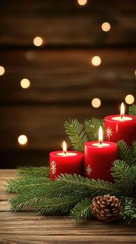 Three red candles on a wooden table with pine cones photo
