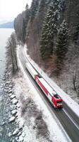 A red and white train traveling down a snowy road photo