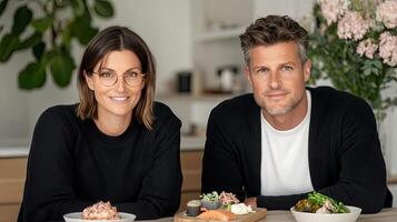 A man and woman sitting at a table with food photo