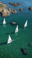 Sailboats in the clear blue water near rocks photo