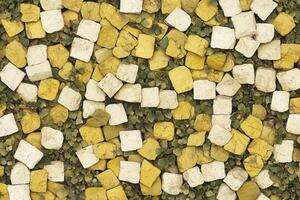 A textured surface of yellow and white squares with greenery. photo