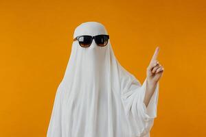 A person in a ghost costume with sunglasses and a white sheet photo