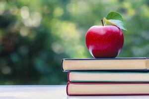 An apple sits on top of three books photo