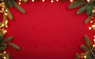 Christmas frame with fir branches and christmas lights on red background photo