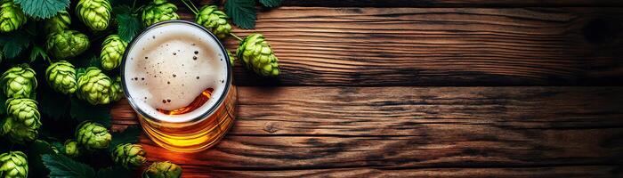 A glass of beer and hops on a wooden table photo