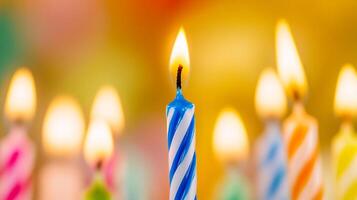 Many colorful birthday candles are lit up in front of a blurred background photo