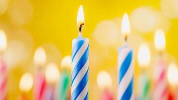Many colorful birthday candles are lit up in front of a yellow background photo
