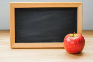 An apple and a chalkboard on a wooden table photo
