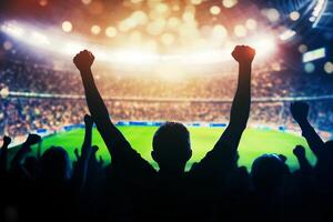 Silhouette of a football fan with hands raised in the air photo