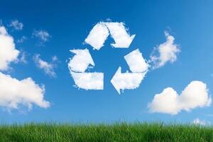 Recycling symbol on grass with blue sky and clouds photo