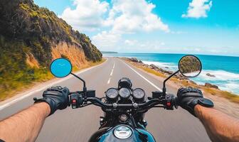 A person riding a motorcycle on a road with the ocean in the background photo