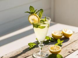 Refreshing lemon mint drink served with fresh lemons and mint leaves on a rustic wooden table in bright summer sunlight. photo