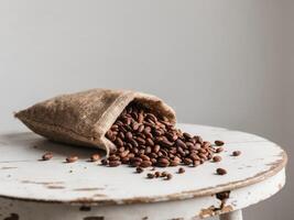 Cocoa beans spilling from a burlap sack on a rustic wooden table. photo