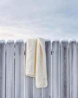 A white scarf is hanging on a fence photo