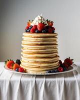 Tower of Pancakes Topped with Fresh Berries and Cream on Buffet Table photo