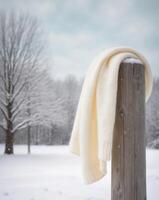 A white scarf is hanging on a wooden post in the snow photo