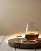 Glass of whisky with ice cubes sitting on wooden table in warm light photo