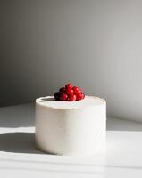 A white cake with a white frosting and red berries on top photo