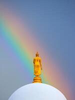 A buddha statue on top of a dome with a rainbow in the sky photo