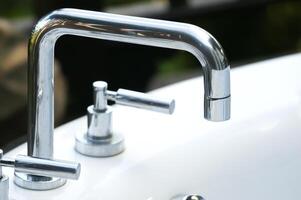 A close up of two faucets on a white sink photo