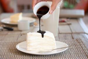 A person pouring a drink over a piece of cake photo