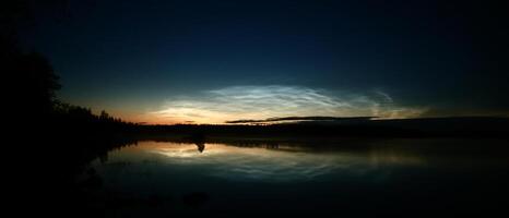 Illuminated cirrus clouds at dusk over lake Malgomaj in Vasterbotten, Sweden photo