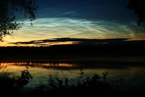 Illuminated cirrus clouds at dusk over lake Malgomaj in Vasterbotten, Sweden photo