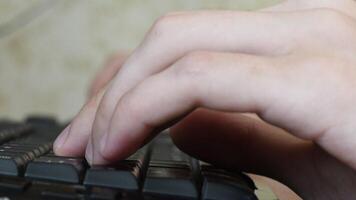 Male fingers using keyboards while playing computer game. Left hand typing on black computer keys with blurred background. game addiction and time-wasting video