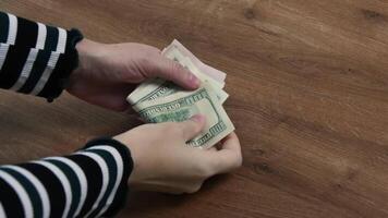 Hands count dollar bills and found rejected dollar bills. Woman holds American cash banknotes and pointing by finger to 100 dollar bill marked by inked symbols. Weird symbols stamped on paper banknote video