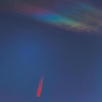Nacreous cloud and a plane with vapor trails illuminated in red photo