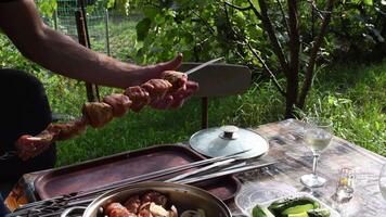 Marinated meat preparation for outdoor picnic barbecue grill. Male hands take raw meat shish kebab and string it on metal skewers. Middle East regional food video