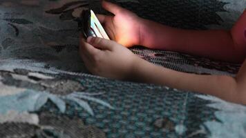 Toddler holds smartphone in hands and watches at device screen. Online watching cartoon using digital gadget while staying at home video
