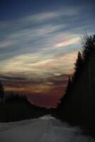 Nacreous clouds in the morning over winter road photo