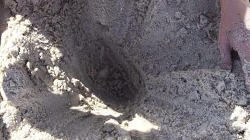Closeup of teenager hands dig wet sand to make pit on beach. Leisure games with sea sand in summer sunny day. Sand castle build activity video