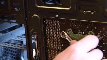 Male hand rotates metal wrench to fix nut on bolt at PC and then holds screw with finger. Screwing of small nut on bolt at core CPU fixer on motherboard. Tools and equipment for computer maintenance video