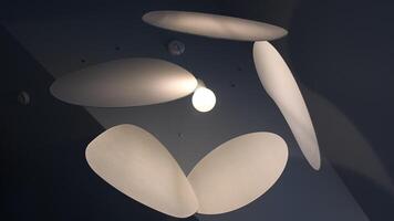 Low-angle shot of glow light bulb of modern chandelier made from ellipse geometric shapes. Lampshade parts turning and fluttering under ceiling. Futuristic monochrome backdrop. Interior decoration video