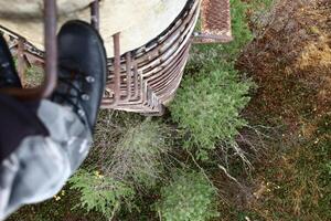 Looking down from a rusty ladder at an old concrete pillar photo