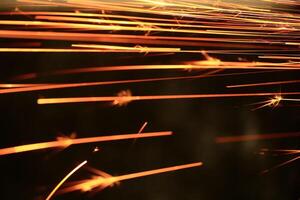 Spraying sparks from metalworking on a dark background photo