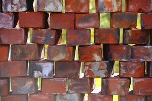 Stacked used bricks in front of blurred background photo