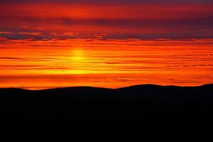 Layered cloudscape and dusk over mountain forest silhouette photo